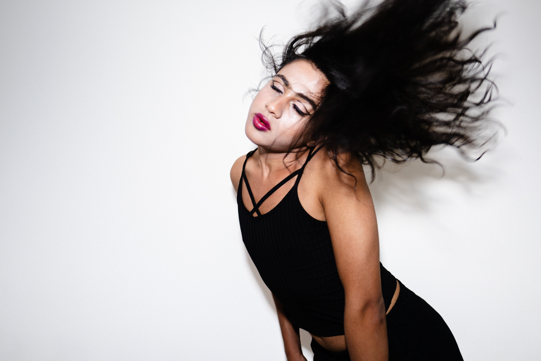 Black-and-white portrait of a dancer with hair in motion against a white background.
